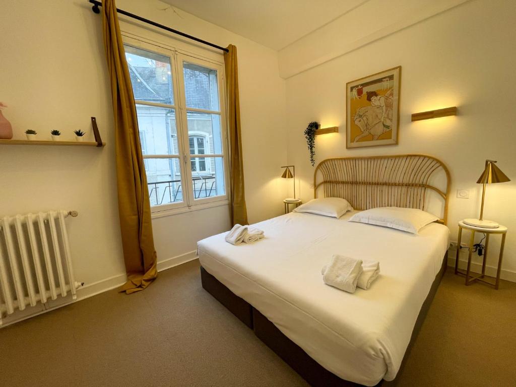 a bedroom with a large white bed with a window at Maison des fleurs in Saint-Aignan