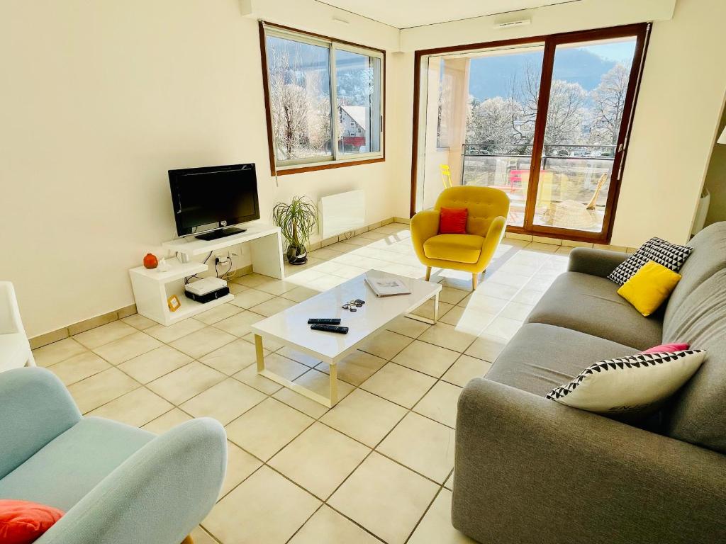 a living room with a couch and chairs and a tv at Bel appart tout confort in Annecy