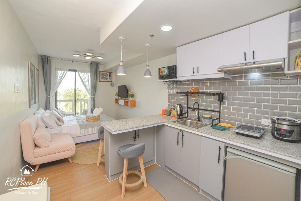 a kitchen with white cabinets and a pink chair at RcplacePH at Pinesuites Tagaytay in Tagaytay