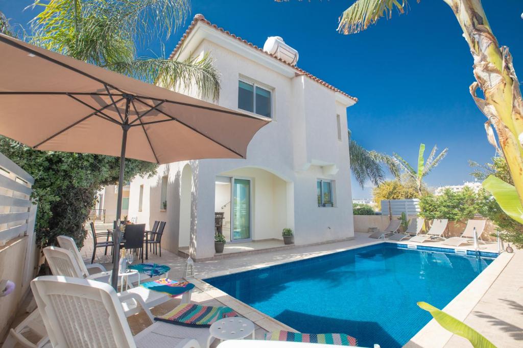 a villa with a swimming pool and an umbrella at George's Villa in Protaras