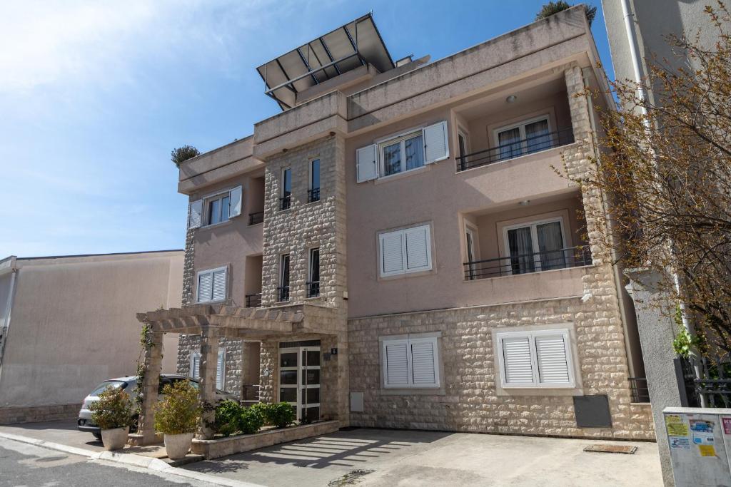 un gran edificio de ladrillo con puertas y ventanas blancas en Petrovac Holiday Apartments, en Petrovac na Moru