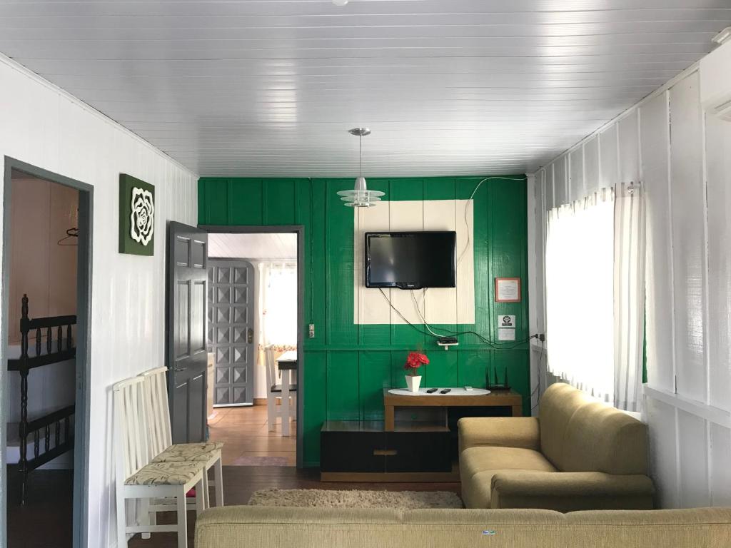 sala de estar verde con sofá y TV en Casa Suzena 300 metros Parque e Praias, en Penha