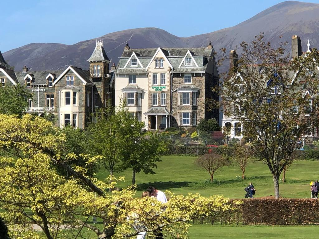 una casa grande en un parque con montañas al fondo en Crow Park Hotel, en Keswick