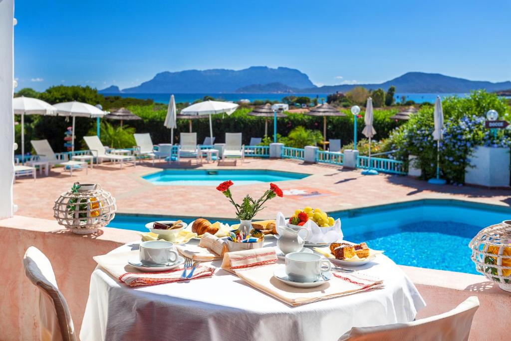 a table with food on it next to a pool at Hotel Stefania Boutique Hotel by the Beach in Olbia