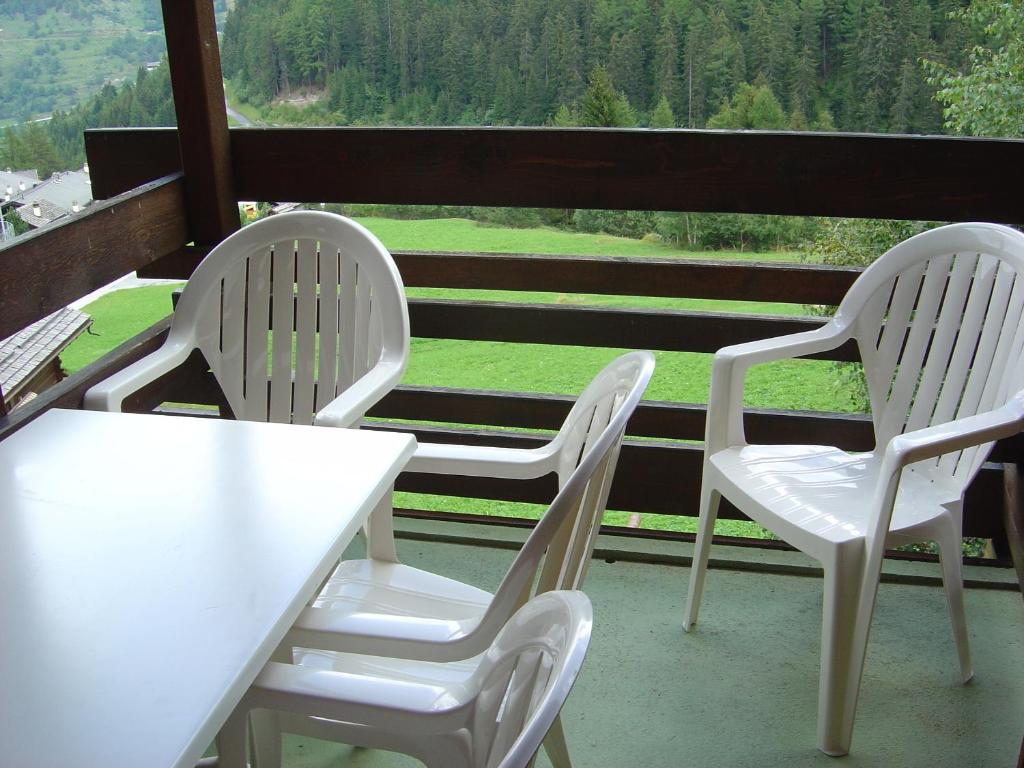 2 weiße Stühle und ein Tisch auf einer Veranda in der Unterkunft Résidence Tarcianne in Grimentz