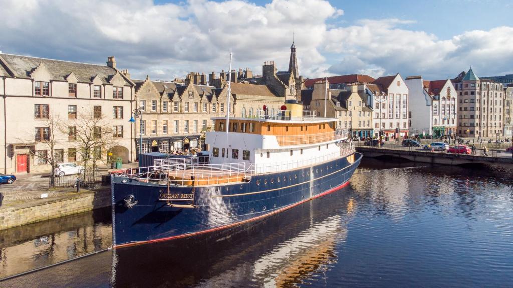 a boat is docked in a river in a city at Ocean Mist Leith in Edinburgh