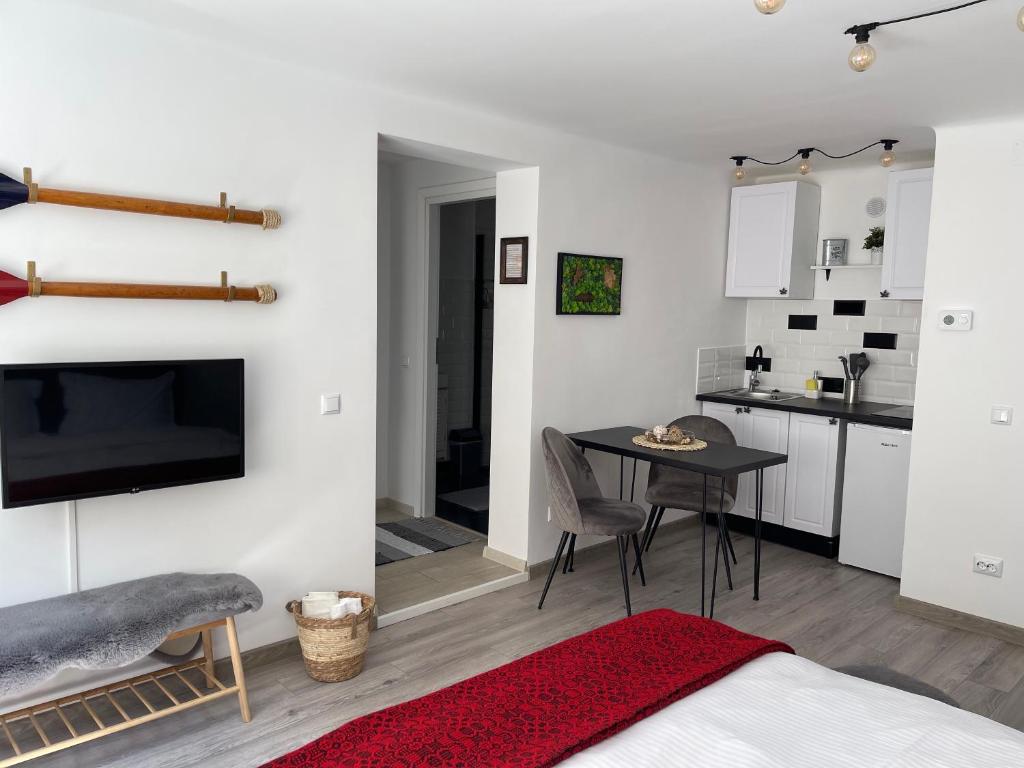 a bedroom with a bed and a table and a kitchen at Maple Lodge in Braşov