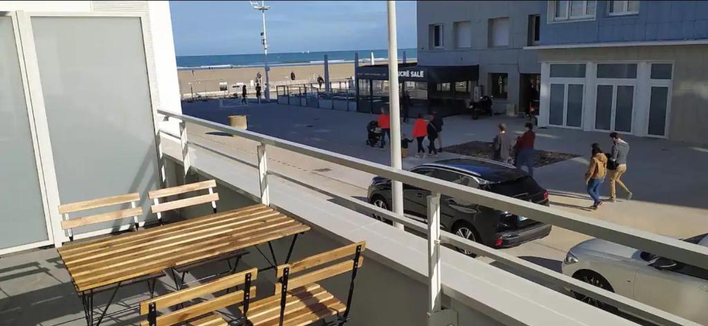 - un balcon avec un banc et une voiture sur la plage dans l'établissement Bel appt neuf - vue mer - terrasse - parking privé, à Dunkerque
