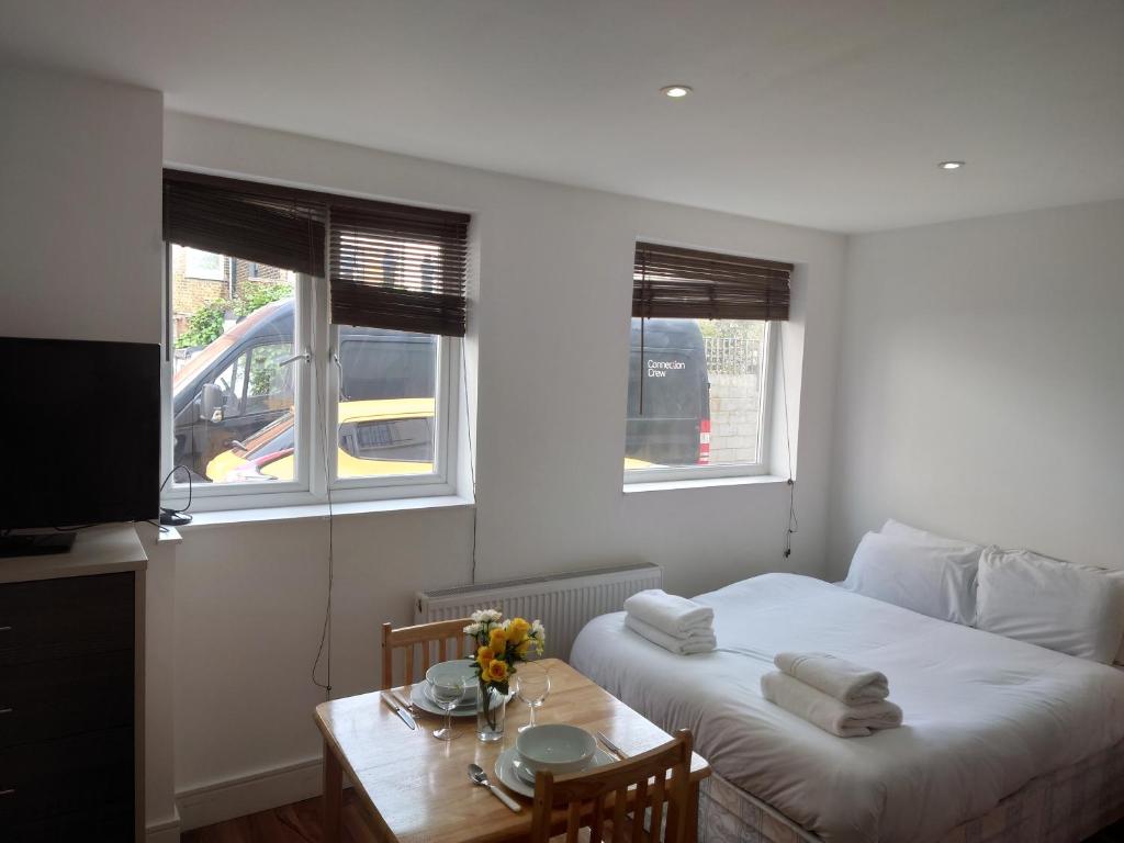 a bedroom with a bed and a table and two windows at City Sparrow 2C in London