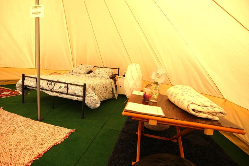 a bedroom with a bed and a table in a tent at Camping Arbre de Vie in Montagnac