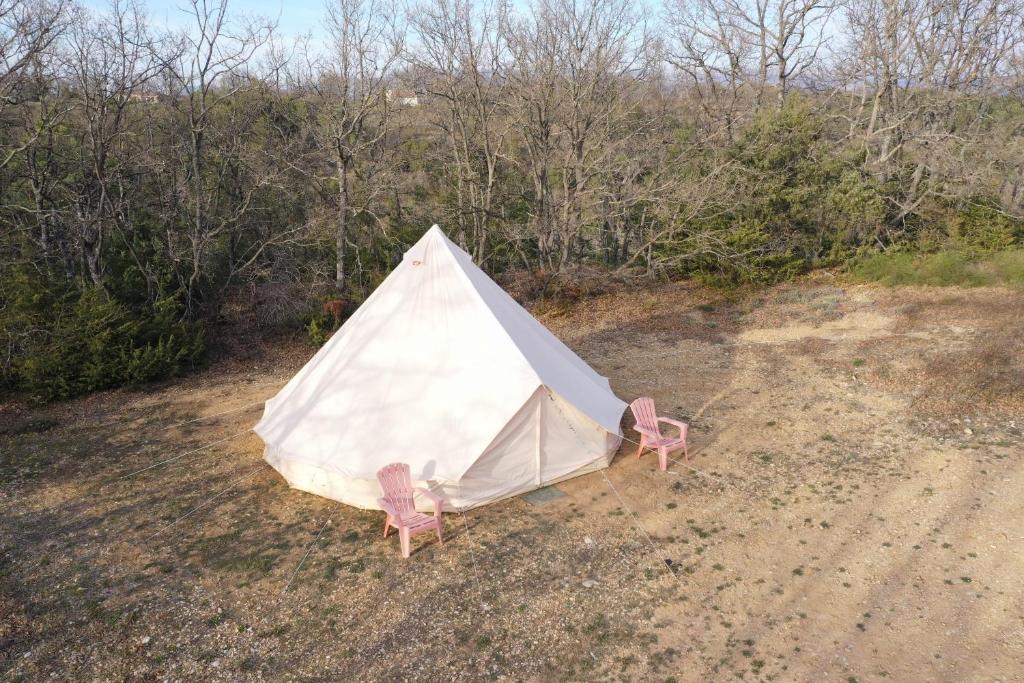 a white tent with two chairs in a field at Camping Arbre de Vie in Montagnac