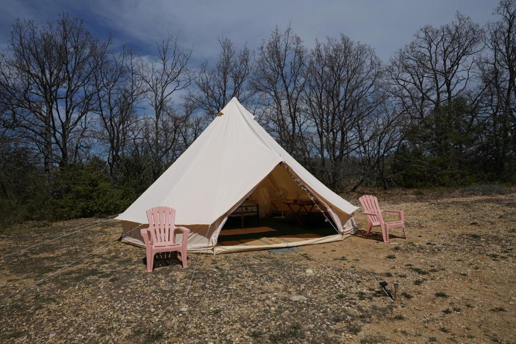 two chairs and a tent in a field at Camping Arbre de Vie in Montagnac