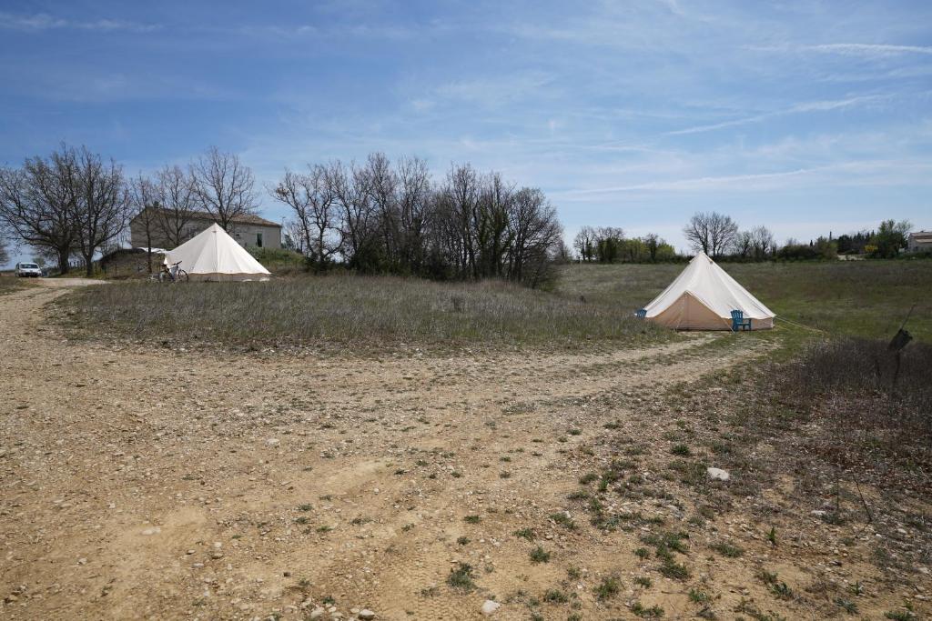 two tents in a field next to a house at Camping Arbre de Vie in Montagnac