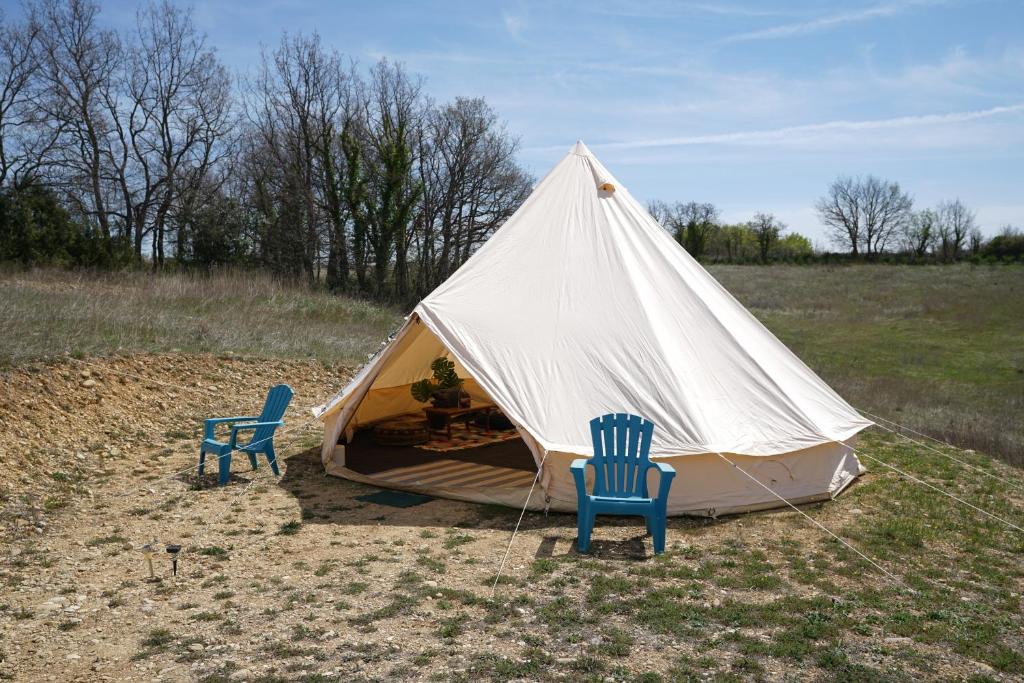 two chairs and a tent in a field at Camping Arbre de Vie in Montagnac
