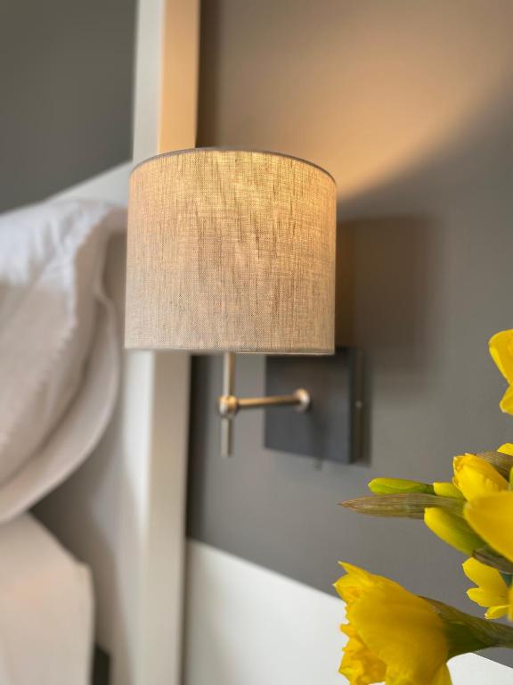 a lamp on a wall next to a bed with flowers at Llandudno Boutique style seaside retreat with stunning views in Llandrillo-yn-Rhôs
