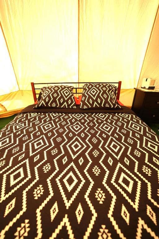 a black and white bed with pillows in a tent at Camping Arbre de Vie in Montagnac