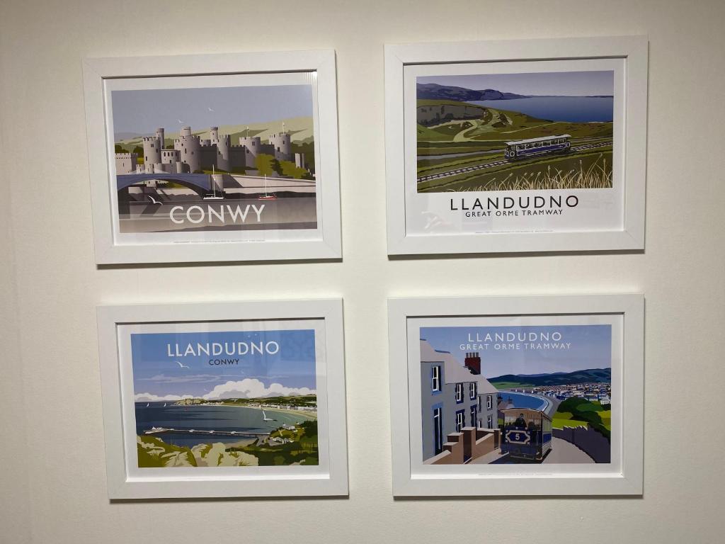four framed posters on a wall in a room at Llandudno Boutique style seaside retreat with stunning views in Llandrillo-yn-Rhôs