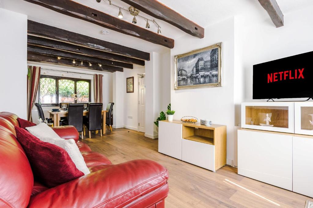 a living room with a red leather couch and a table at Sunshine Cottage by Happy Sunshine Stay in Golborne