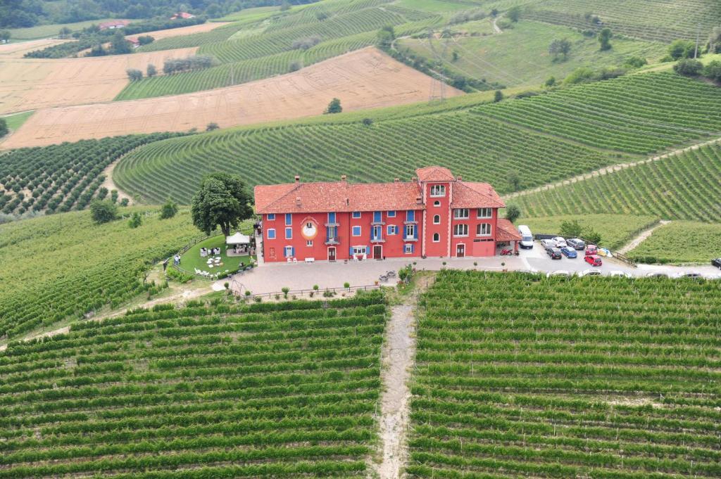 une vue aérienne sur un bâtiment rouge dans un vignoble dans l'établissement Bricco Rosso, à Farigliano