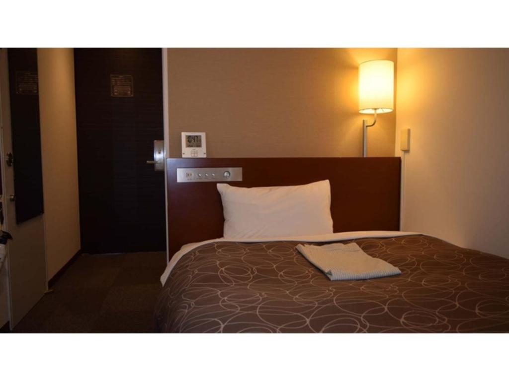Una habitación de hotel con una cama con una toalla. en Hotel RESH Tottori Ekimae - Vacation STAY 47404v, en Tottori