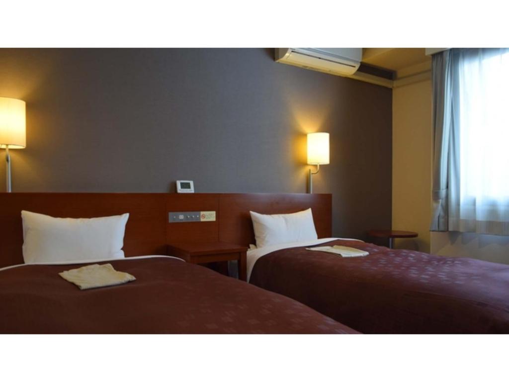 um quarto de hotel com duas camas e duas lâmpadas em Hotel RESH Tottori Ekimae - Vacation STAY 47411v em Tottori