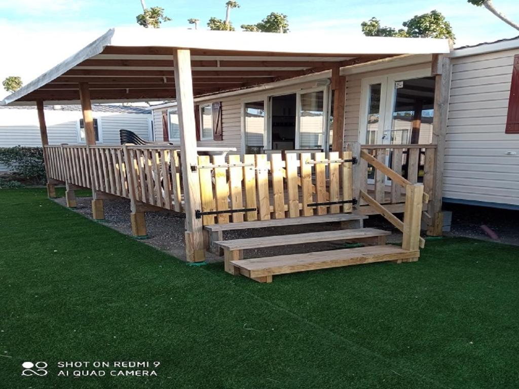 une maison avec une terrasse couverte dotée d'une rampe en bois et d'un kiosque dans l'établissement MOBIL HOME CAMPING LES SABLES DU MIDI, à Valras-Plage