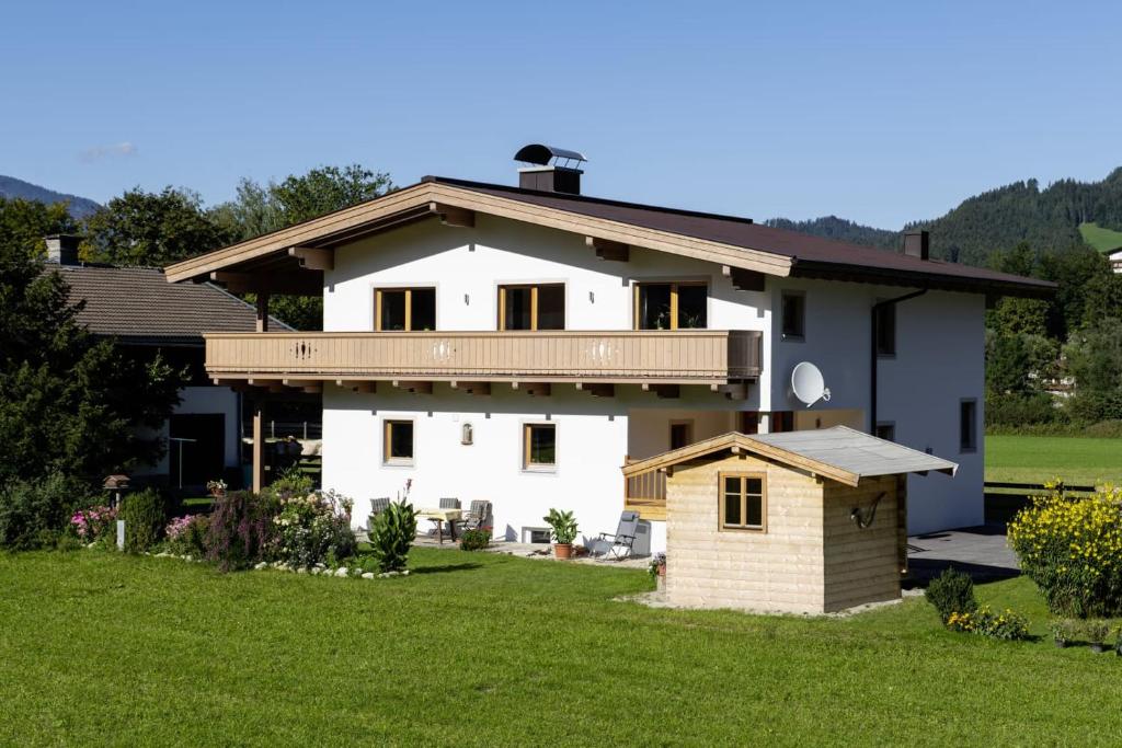 uma casa branca com um deque e uma casa de cães em Ferienwohnung Leitinger em Sankt Martin bei Lofer