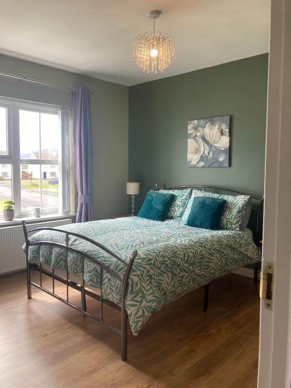 Schlafzimmer mit einem Bett mit blauer Bettwäsche und einem Kronleuchter in der Unterkunft 2 Sea crest Bundoran in Bundoran