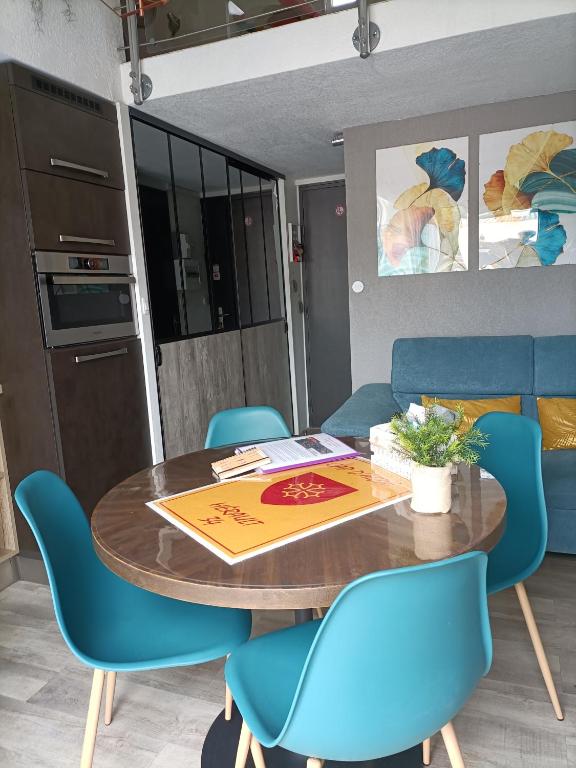 une salle à manger avec une table et des chaises bleues dans l'établissement Résidence les Estivales, au Cap d'Agde