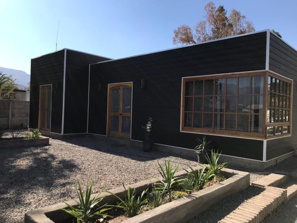 een zwart huis met glazen deuren in een tuin bij Cabaña de 1 ambiente para hasta 4 personas in Putaendo