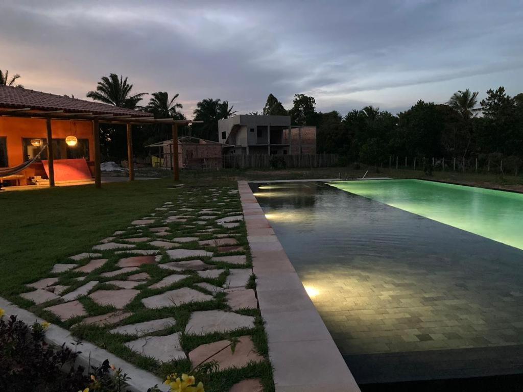 a swimming pool with a stone walkway next to a house at Pousada Flor do Rio in Caraíva