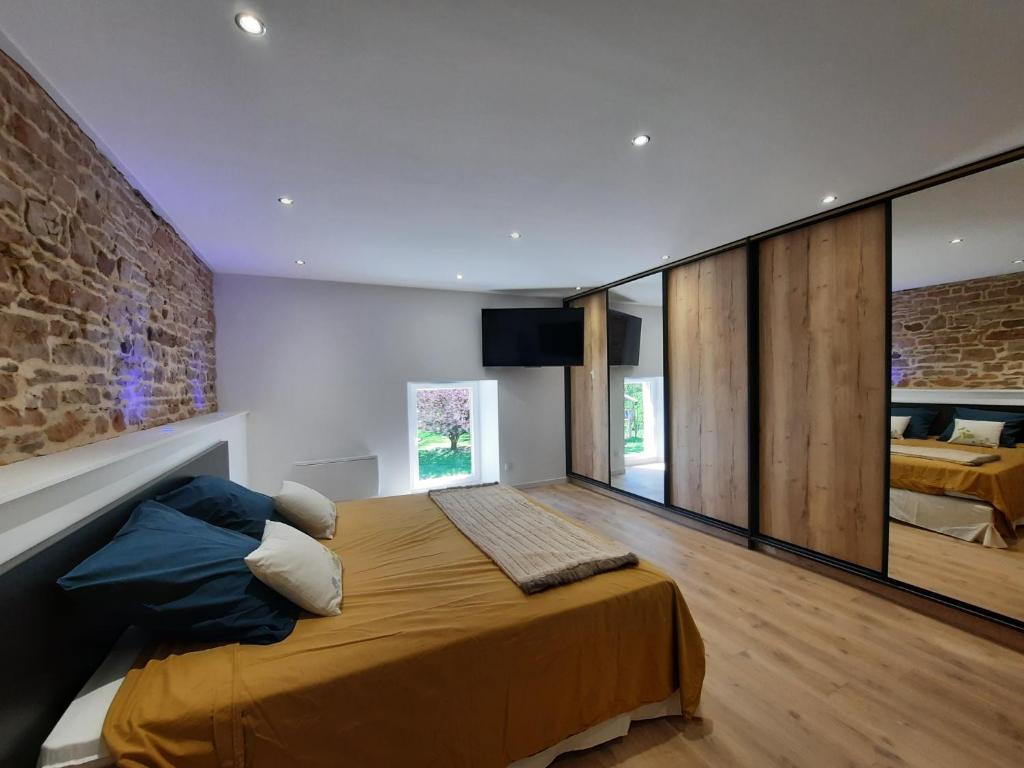 a bedroom with a large bed and a brick wall at Les étangs du moulin d'Harcy in Lonny