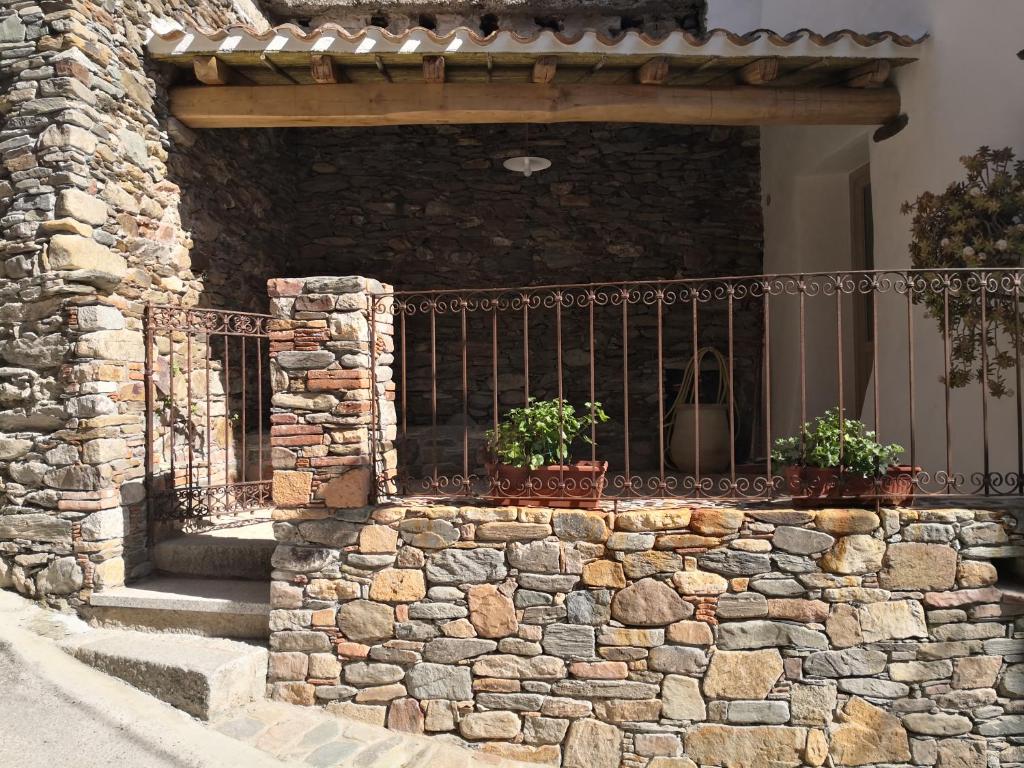 ein Steingebäude mit einem Zaun und zwei Topfpflanzen in der Unterkunft Domu Antiga in Tertenìa