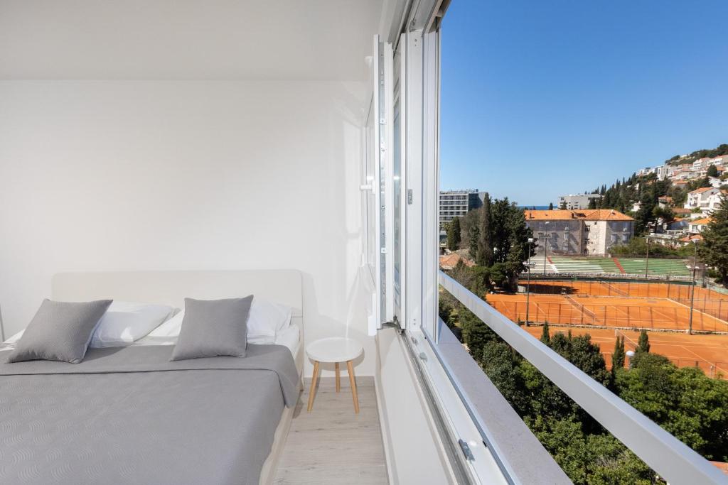 a white balcony with a bed and a table at Tennis apartment Dubrovnik, FREE parking, beach in Dubrovnik