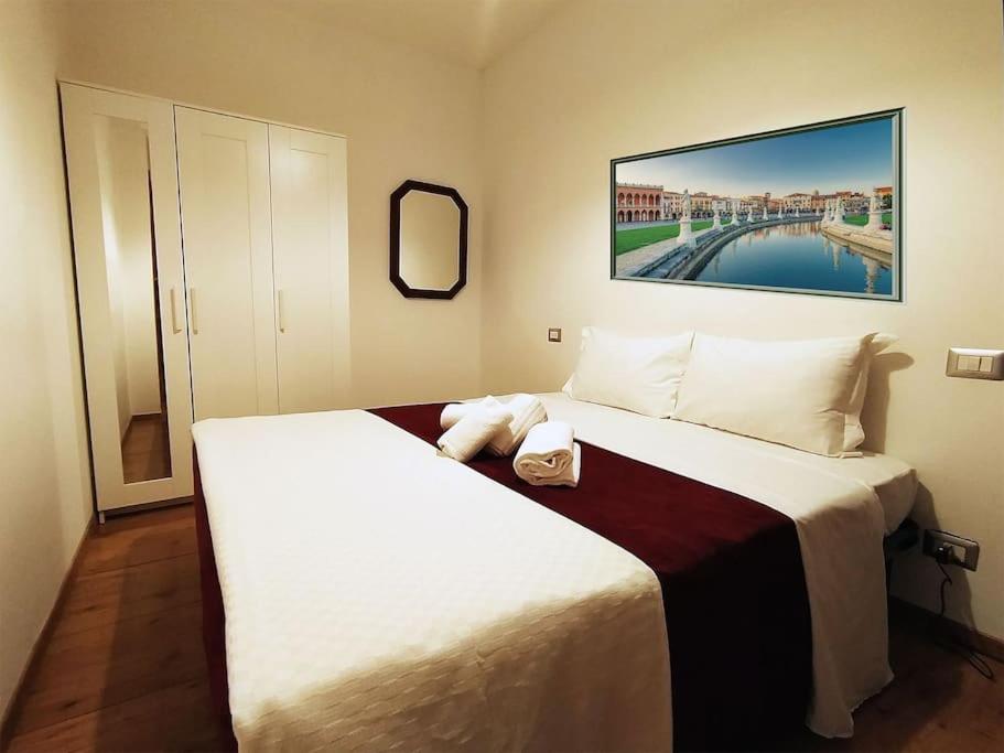 een slaapkamer met een groot wit bed en een spiegel bij Appartamento Perosi in Padua