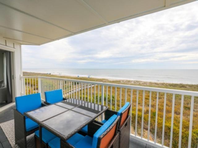 a table and chairs on a balcony with a view of the ocean at Carolina Beach Dreamin - light filled south side END unit, Ocean views from most rooms! Private beach access! condo in Carolina Beach