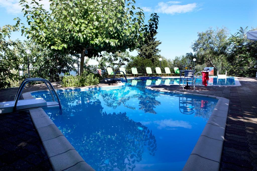 a swimming pool with blue water in a yard at Dafnoudi Hotel Apartments in Fiskardo