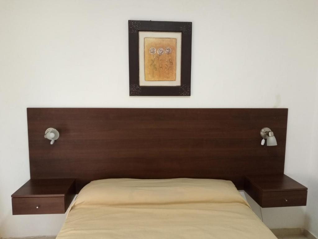 Una cama con cabecero de madera y un cuadro encima. en LAS ViOLETA'S, en Federación