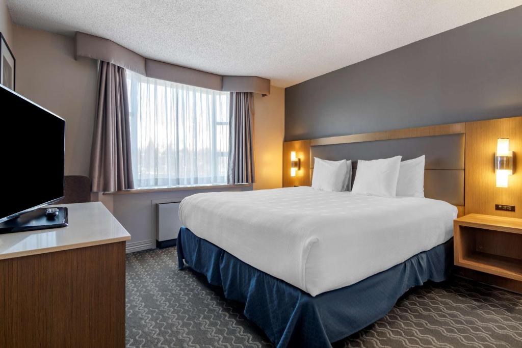 a hotel room with a large bed and a television at Best Western Plus Vancouver Airport Hotel in Vancouver