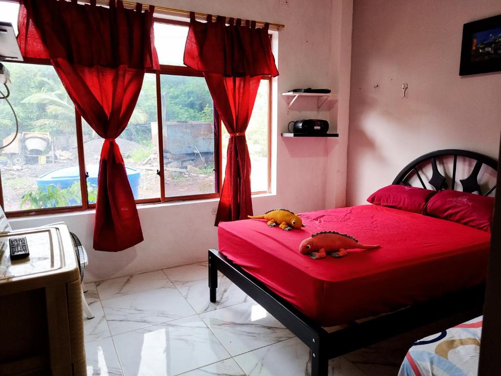 two dogs laying on a red bed in a bedroom at La Casa de Amelia in Puerto Baquerizo Moreno