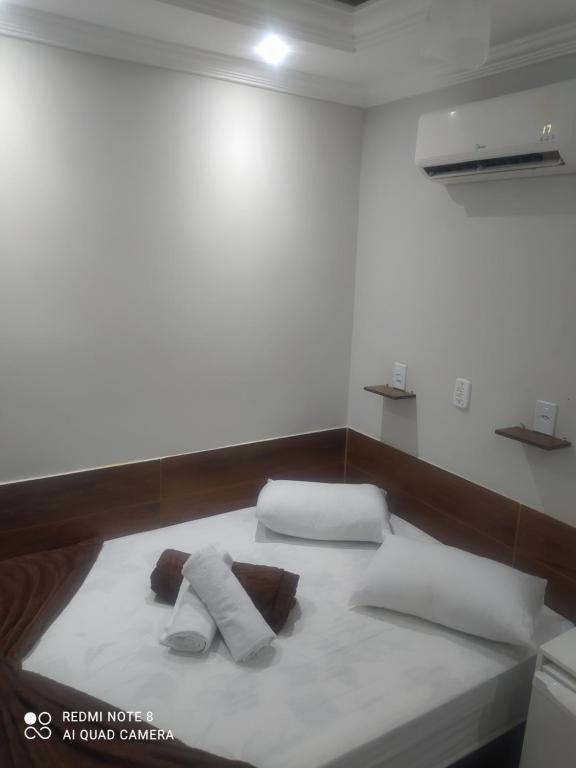 a bed in a room with two pillows on it at Pousada Quarto Casal com ar,frigobar, garagem in Aparecida
