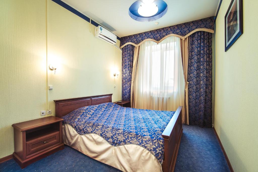 Yal Hotel في كازان: غرفة نوم صغيرة بها سرير ونافذة