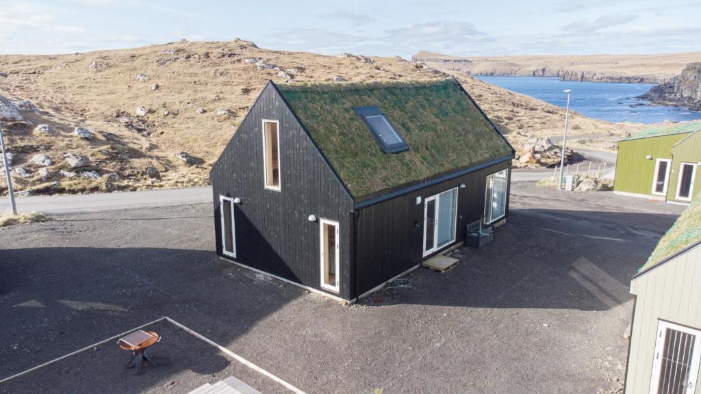 a small black house with a grass roof at Vacation Home / Scenic Nature / Sandoy / Beach in Sandur