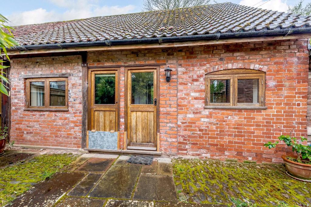 a brick house with a wooden door and windows at The Bothy in Ross on Wye
