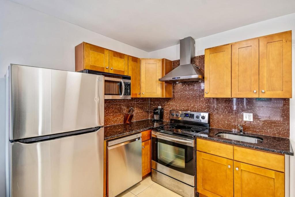 a kitchen with wooden cabinets and a stainless steel refrigerator at Stylish & Great location next to the convention center in Philadelphia