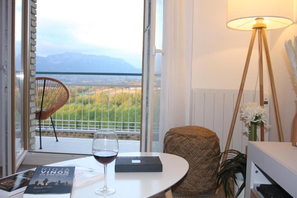 um copo de vinho numa mesa em frente a uma varanda em Apartamentos La Herradura Viñas em Haro
