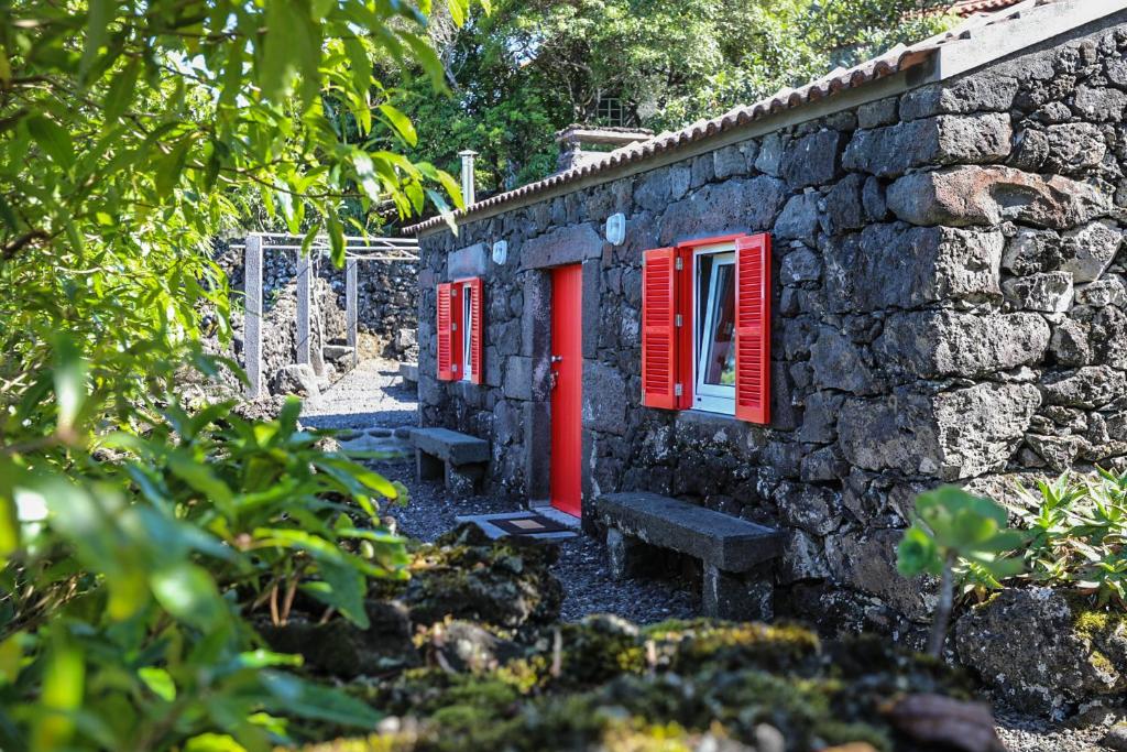 サン・ロケ・ド・ピコにあるAdega Baía Azul - The essence of Picoの赤窓とベンチ付きの石造りの建物