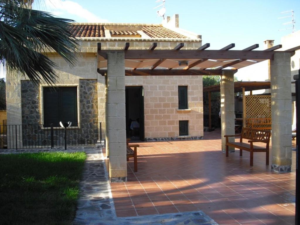 a wooden pergola with two benches on a patio at Villa Emiri in Cefalù
