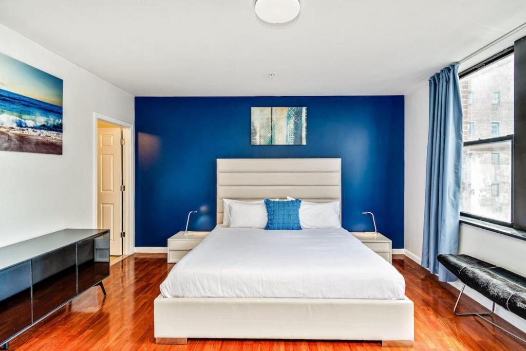 Un dormitorio con una pared azul y una cama blanca en The place to stay! en Filadelfia
