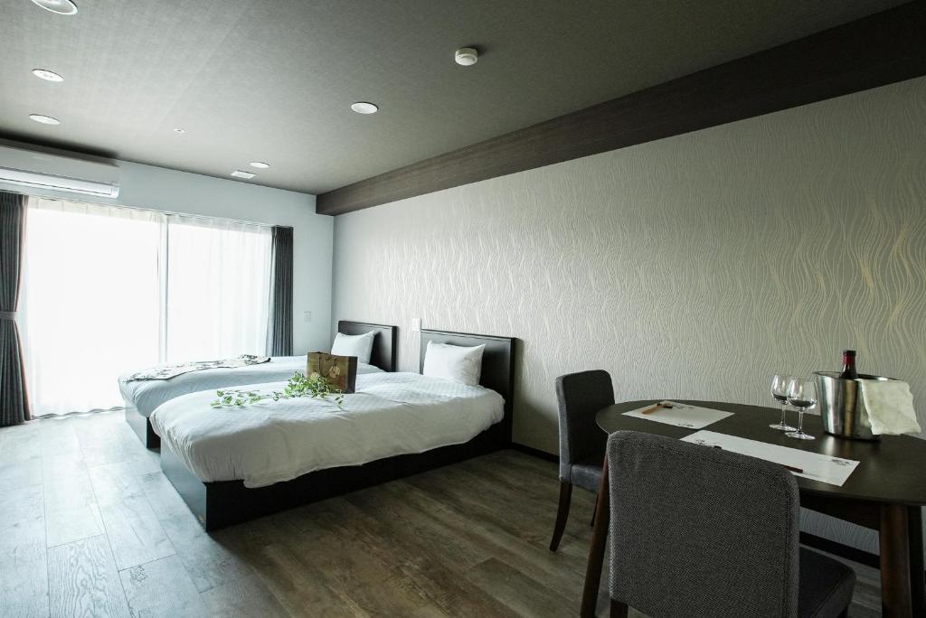 a bedroom with two beds and a table and a dining room at Vacation Rent 金沢 in Kanazawa